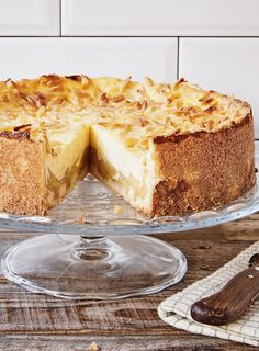 a cheesecake on a glass cake plate with one slice missing