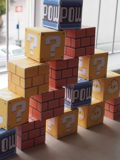 several blocks with question marks on them are stacked up in front of a window,