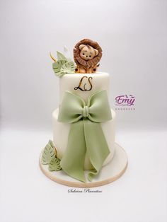 a white cake with a green bow and a lion on top