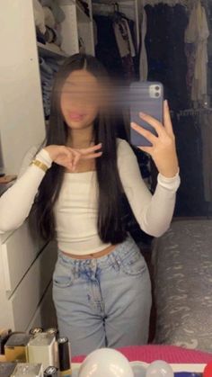 a woman taking a selfie with her cell phone in front of her face and clothes behind her