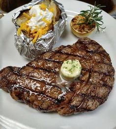 steak, potatoes and salad on a plate with foil wrapper over the top for garnish