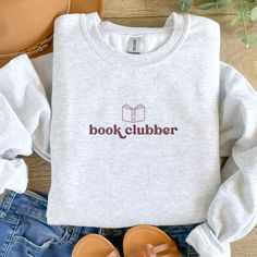 "Hello, book clubbers! This sweatshirt is super cozy and features a simple retro font text \"book clubber\" with an open book above. The sweatshirt is the color Ash (a very light heather grey).  FABRICATION - 50% cotton, 50% polyester - Medium-heavy fabric FIT - Unisex fit - this has a loose fit! - True to size (see size chart in listing) - Ribbed knit collar - For a relaxed look, stick with your typical size. - If you want the trendy oversized look, size up! I recommend 1-2 sizes. CARE INSTRUCT Book Club Sweatshirt, Book Club Merch, Christmas Book Club Party, Book Club Shirts, Book Club Gift Ideas, Book Club Ideas, Book Club Party, Book Club Gifts, Book Club Parties