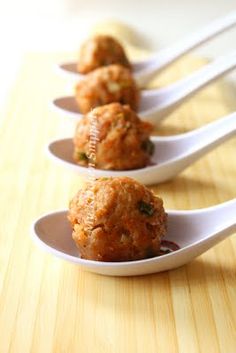 four spoons with food on them are lined up in the shape of meatballs