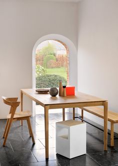 a table and two chairs in a room with an arched window on the far wall