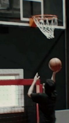 a man in black shirt playing basketball on court with hoop and net behind him,