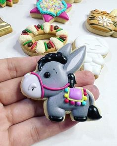 a hand is holding some decorated cookies in the shape of an elephant and other items