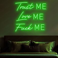 a green neon sign that says trust me love me fuk me on the wall