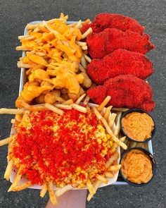 a tray filled with fried food next to dipping sauces and condiments on the side