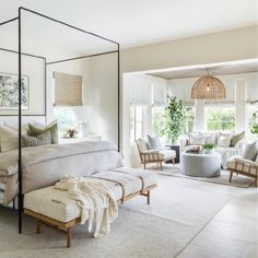 a white bedroom with four poster bed and lots of furniture