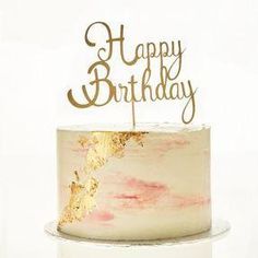 a white cake topped with a pink and gold frosted happy birthday cake topper