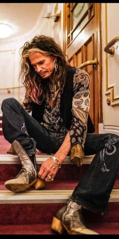 a man with long hair sitting on the steps