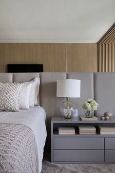 a white bed sitting next to a gray dresser with two lamps on top of it