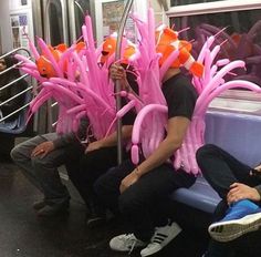 some people sitting on a train with pink and orange decorations