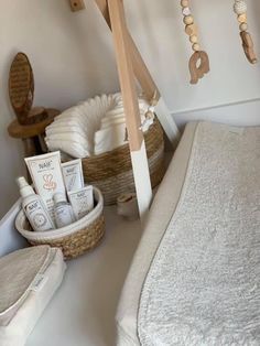 a white bed sitting next to a basket filled with baby items on top of a table