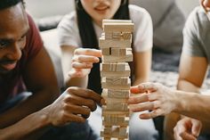 three people playing with wooden blocks on the floor