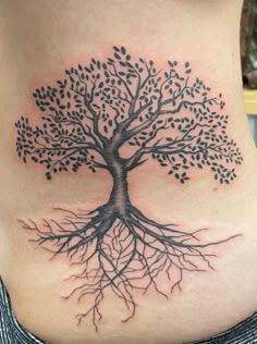 a woman's stomach with a tree tattoo on it