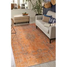 an orange rug in a living room with a couch and chair next to the window