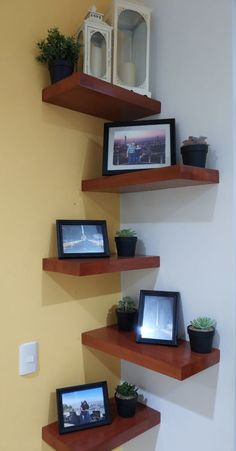 three wooden shelves with pictures and plants on them