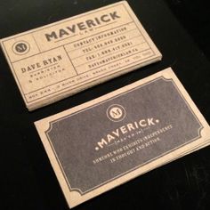 two business cards sitting next to each other on top of a black table with white writing