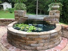 a fish pond in the middle of a brick wall and surrounded by water lilies