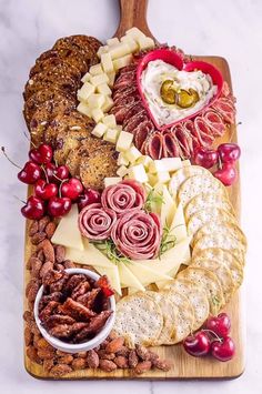 an assortment of cheeses, meats and crackers on a wooden platter