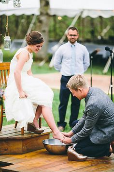 a man kneeling down next to a woman in a white dress on top of a wooden platform