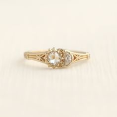 an antique diamond ring with three stones on the side, sitting on a white surface