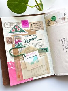 an open book with stamps on it next to a plant