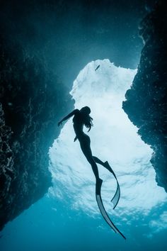 a woman is swimming in the water near rocks