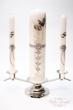 three white candles are on a silver stand