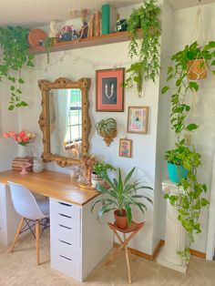 a room with some plants on the wall and a desk in front of two mirrors