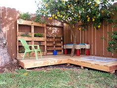 a wooden deck in the middle of a yard next to a tree and a green chair