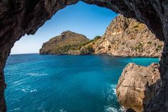 an ocean view from inside a cave with blue water and mountains in the background