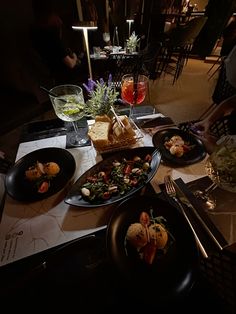 a table topped with black plates filled with food