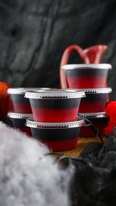 three red cups sitting next to each other on top of a wooden table covered in yarn