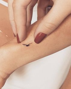 a woman's arm with a small bird tattoo on it