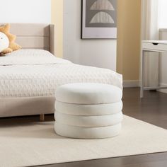 a white bed sitting on top of a hard wood floor next to a table with a teddy bear