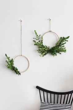 two wreaths hanging on the wall next to a chair with a pillow and pillows