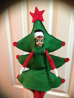 an elf is standing next to a christmas tree