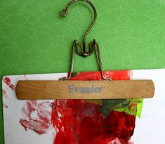 a piece of wood hanging from a hook on a green wall next to red and white papers