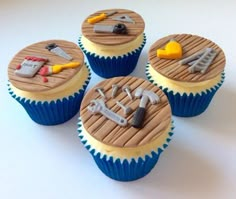 four cupcakes with tools on them sitting on a table