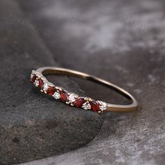 a gold ring with red and white stones on it sitting on top of a rock