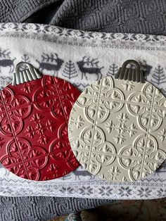 two red and white ornaments sitting on top of a blanket