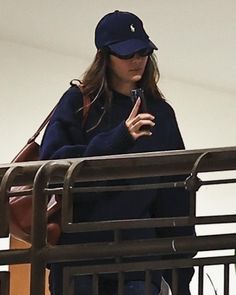 a woman wearing a blue hat is looking at her cell phone while standing on a balcony