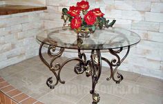 a glass table with some red flowers on it in front of a white brick wall