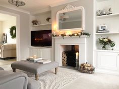 the living room is decorated in white and has a fireplace with candles on it as well