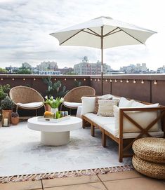 an outdoor living area with wicker furniture and umbrellas on the roof top deck