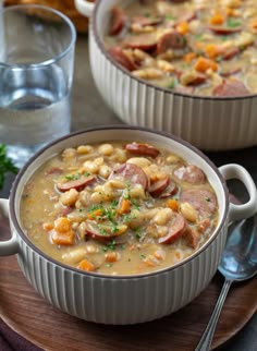 two bowls filled with soup on top of a wooden plate