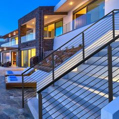 a modern house with stairs leading to the upper floor and second story balcony area at dusk