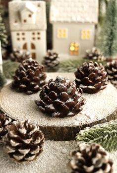 pine cones are sitting on a piece of wood next to small houses and fir trees